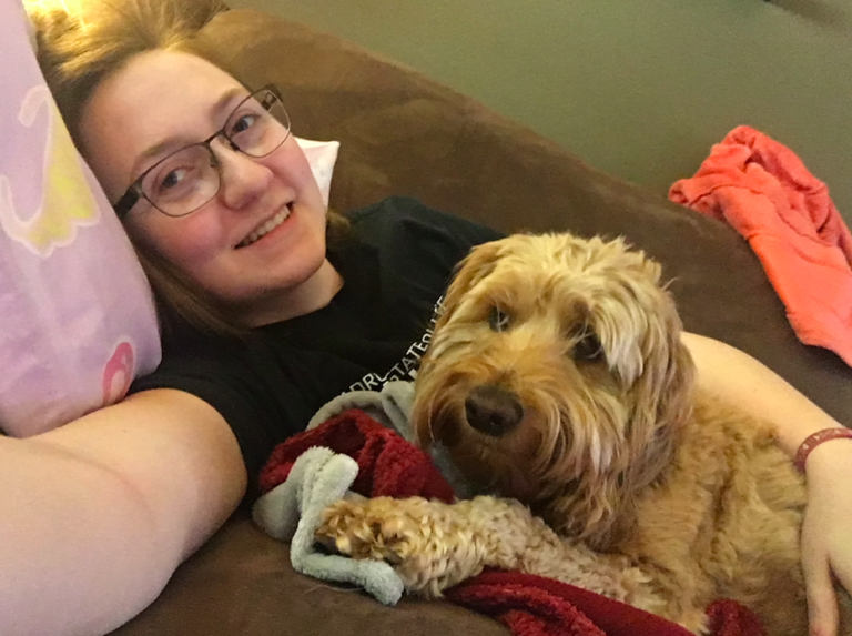 Sierra Needles on the couch with her dog Lilly, where she would spend hours watching YouTube travel vlogs.