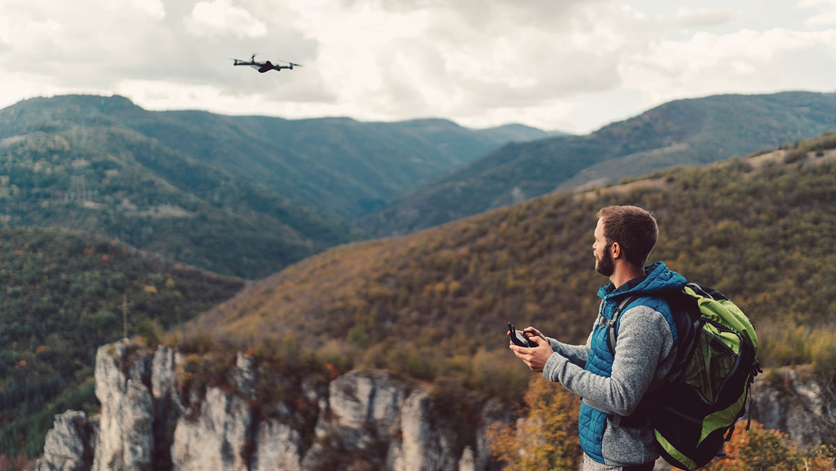 Man flying drone in front of mountain landscape